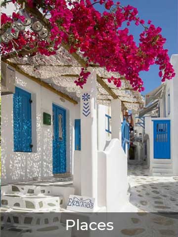 Charming Greek island street with whitewashed buildings, vibrant blue doors, and blooming pink bougainvillea under a clear sky